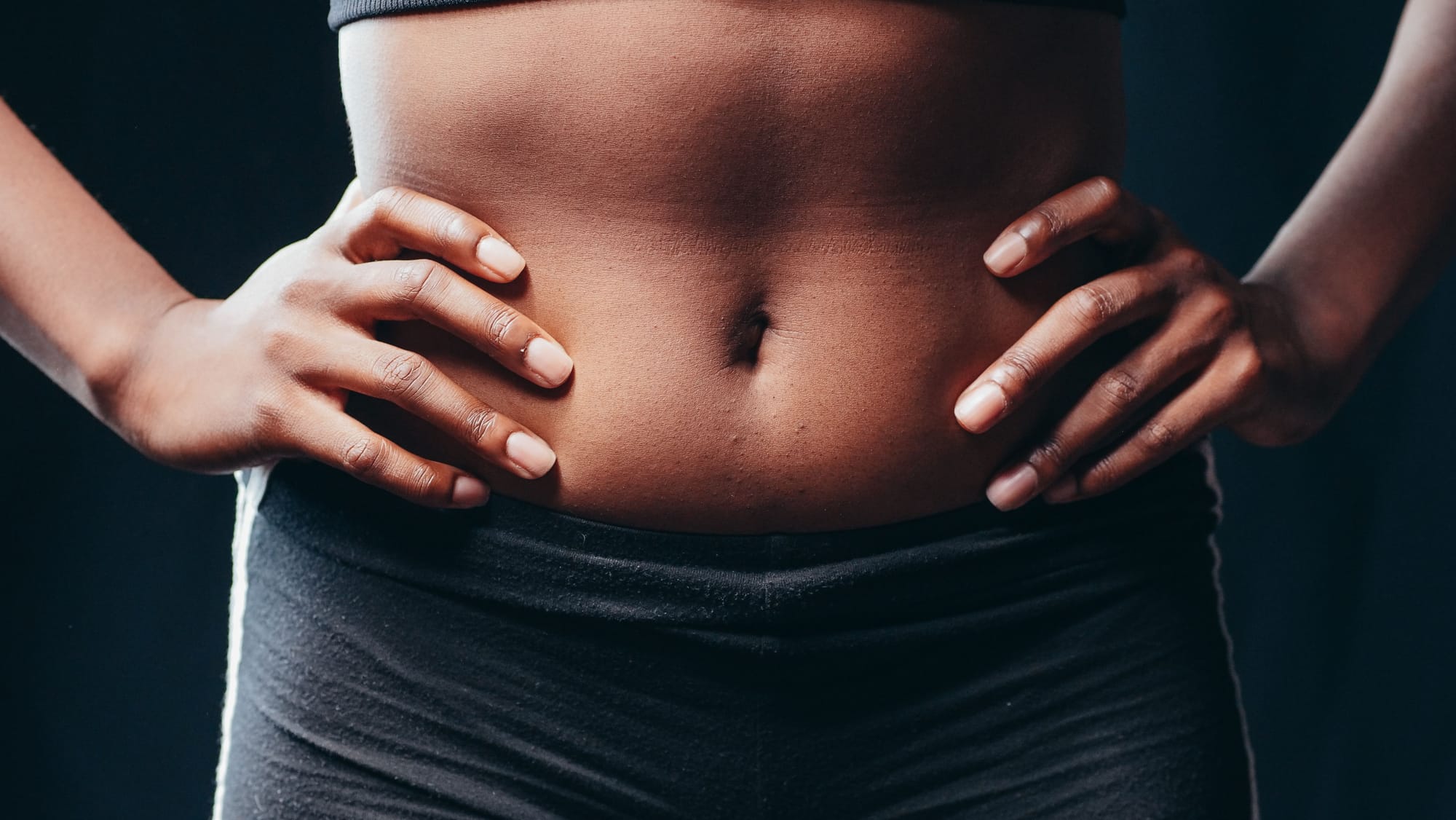 A woman's hands resting on her lower abdomen