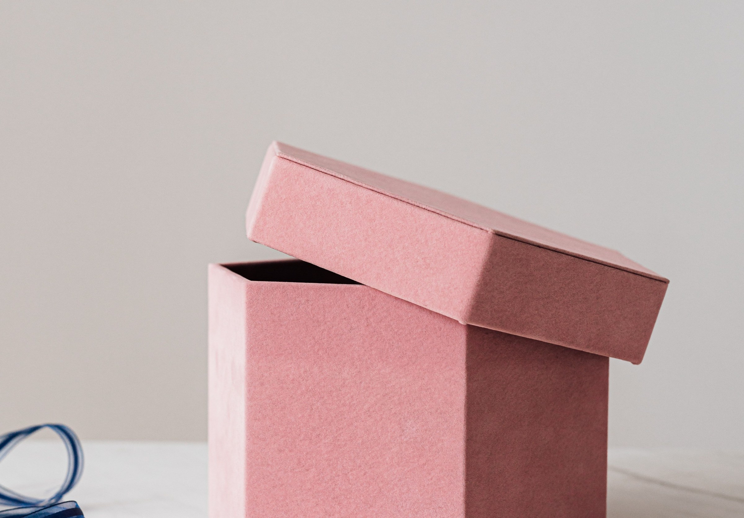 A plain dusty-pink box with its lid resting ajar